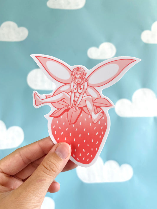 Cute and sexy fairy straddling a strawberry in a sexually suggestive manner, nsfw anime fairy sticker photographed in front of a backdrop of cloud shapes